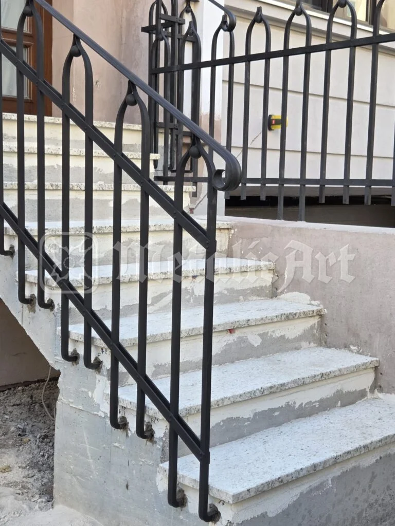 Scară exterioară cu balustradă din fier forjat și mână curentă rotundă.
