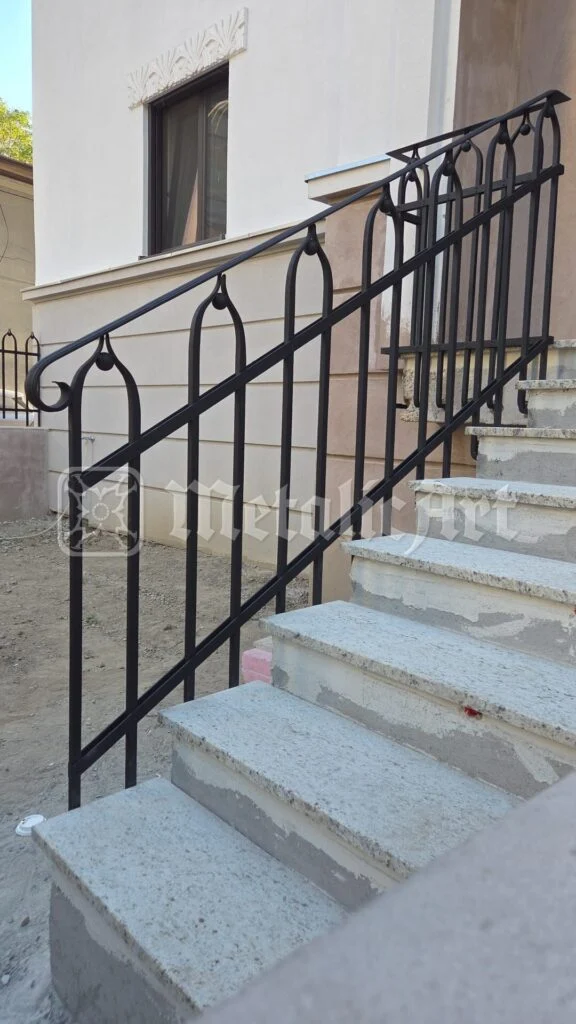 Mână curentă din țeavă rotundă, urmând treptele de beton.
