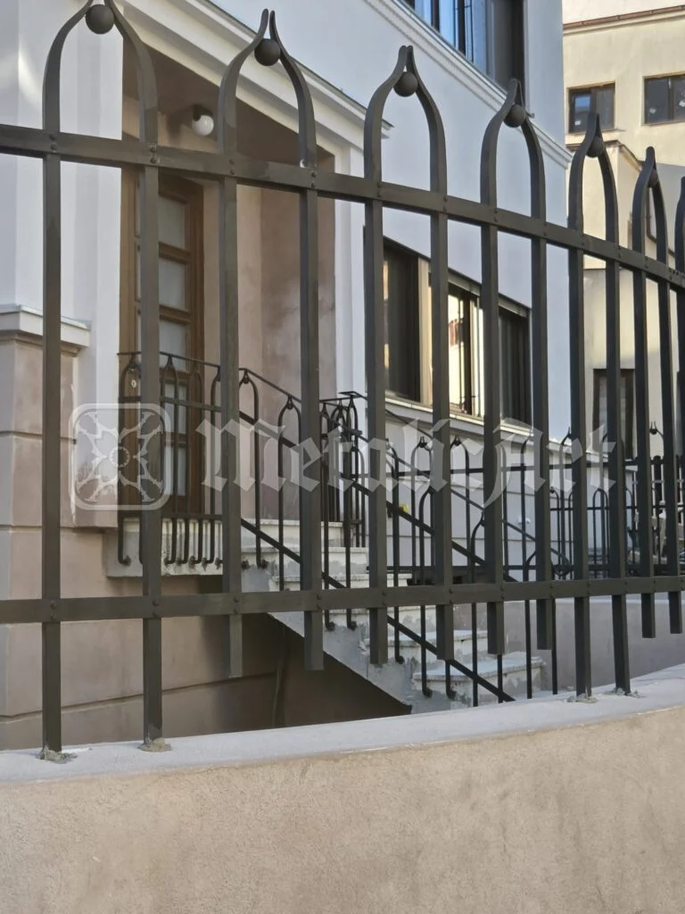 Balustrada scării și gardul casei, văzute dintr-o parte.