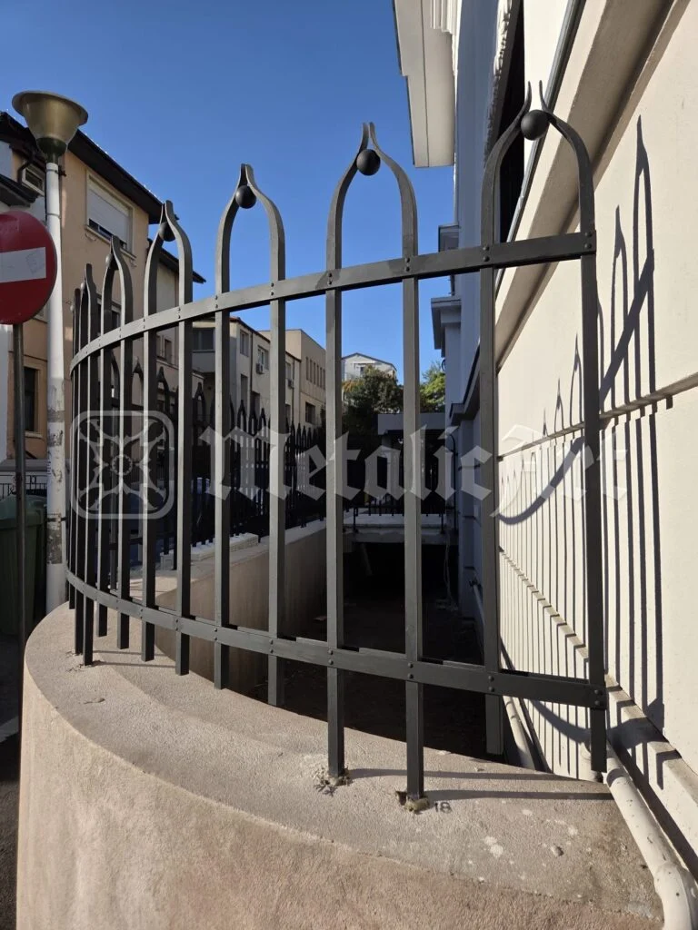 Balustradă curbată din fier forjat, pe zidul rotunjit al terasei.