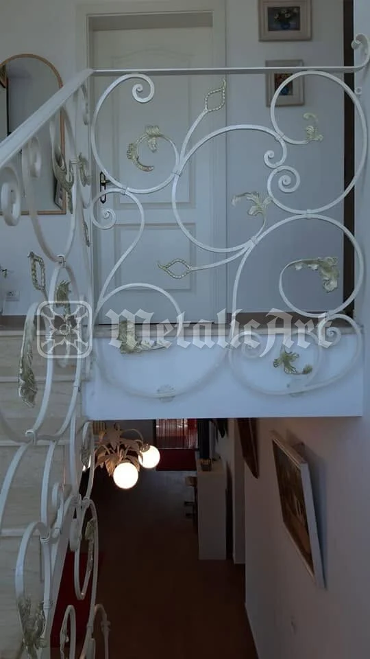 Balustrada albă cu volute și frunze aurite, deasupra holului.