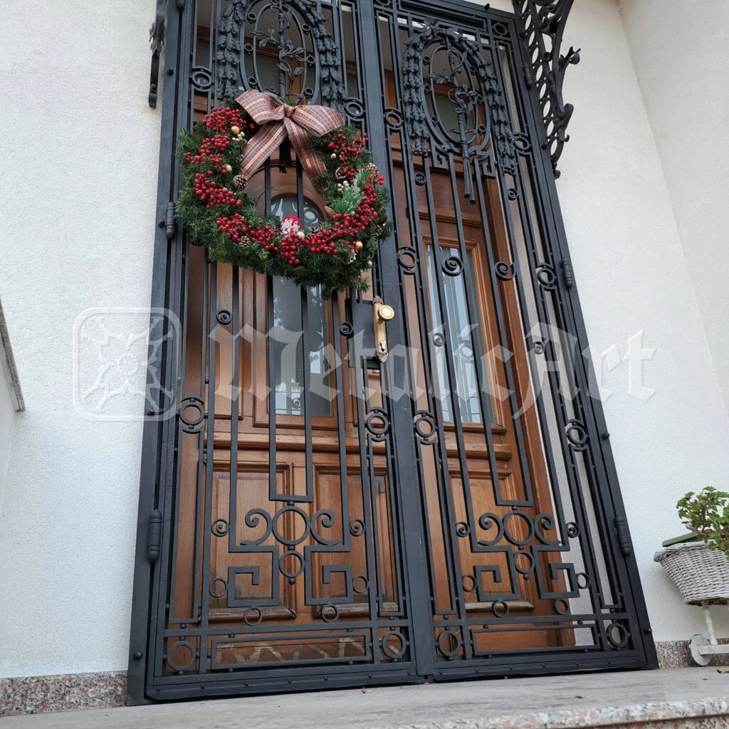 Ușa de intrare cu grilaj forjat, cu coroniță de sărbători agățată pe ea.