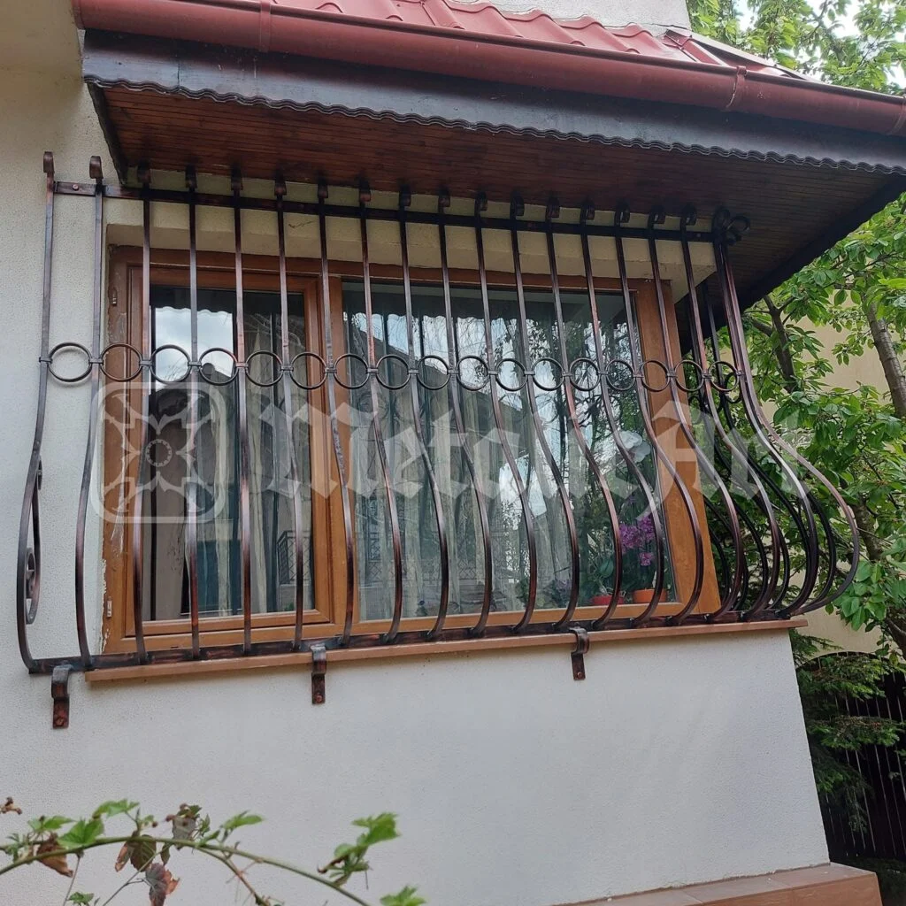 Grilajul ferestrei late, sub streașina de tablă.