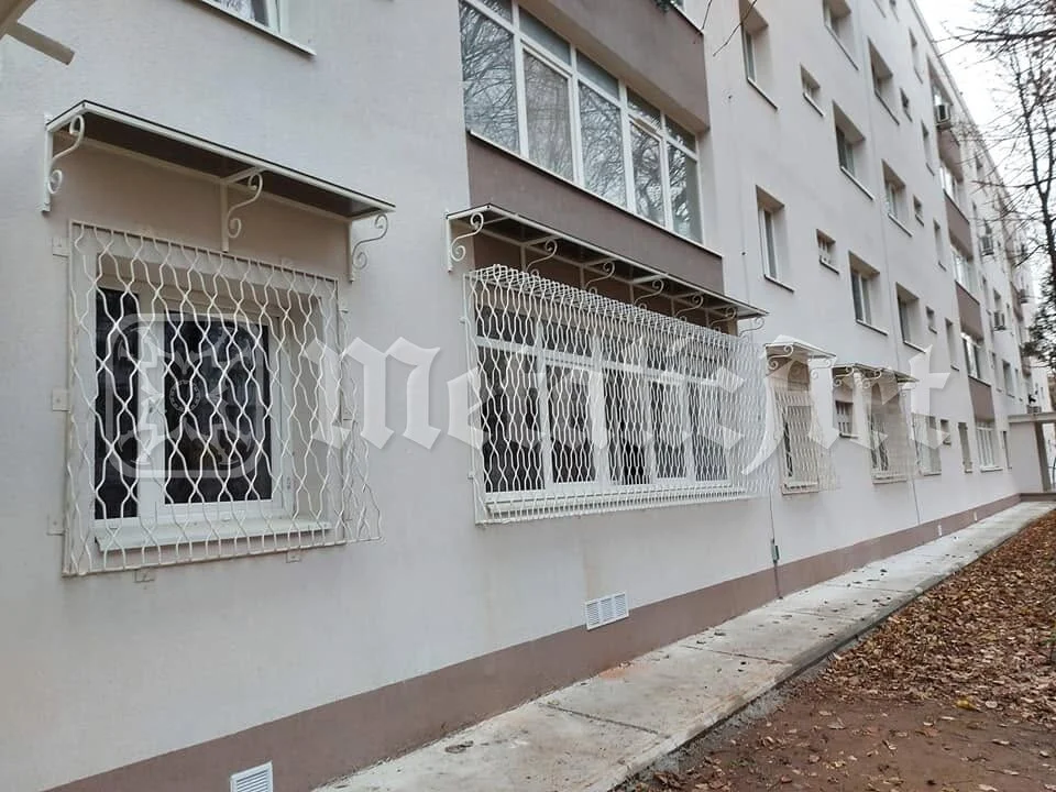 Fațada blocului cu grilajele montate, văzută de pe alee.