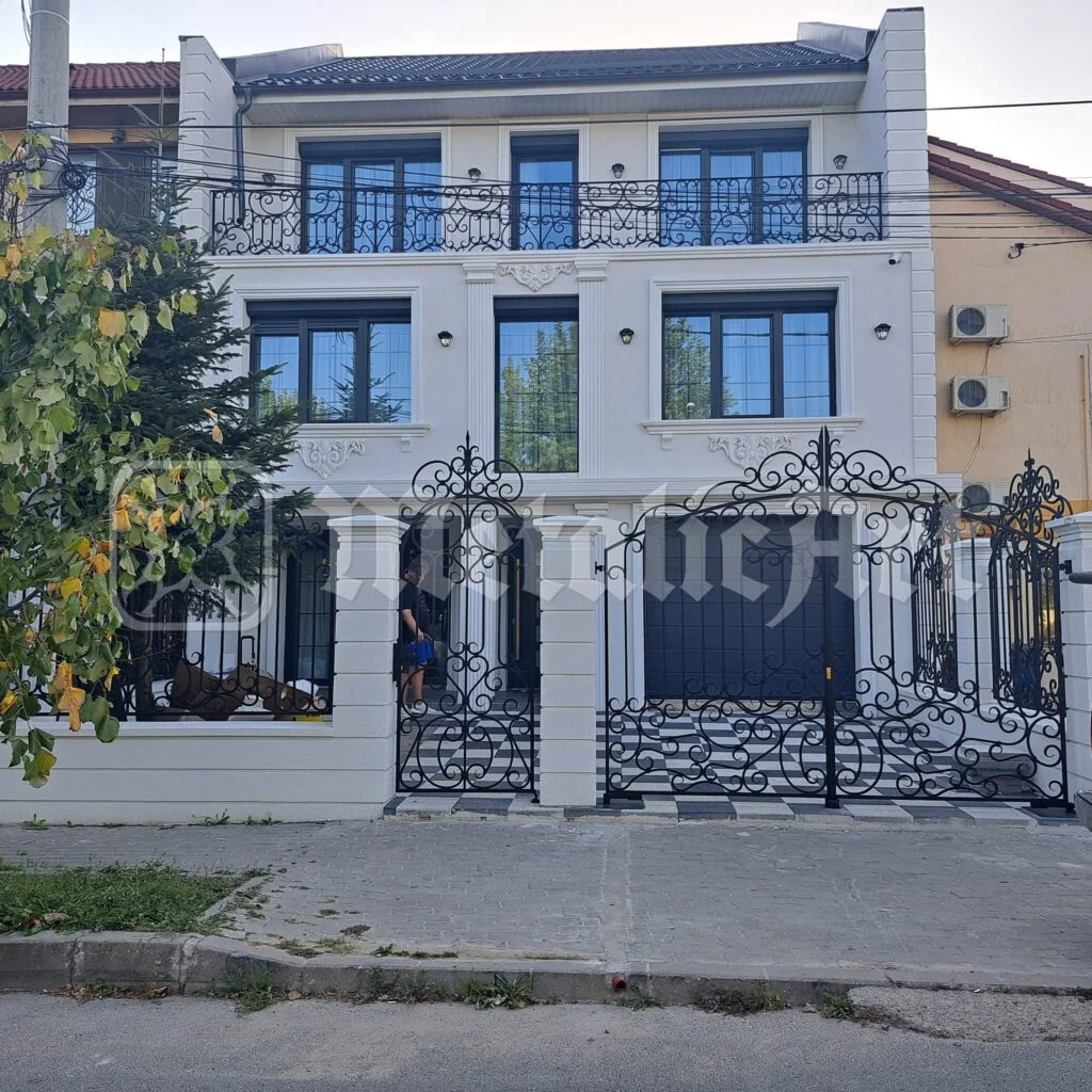 Casa văzută din stradă, cu gardul și balcoanele forjate.