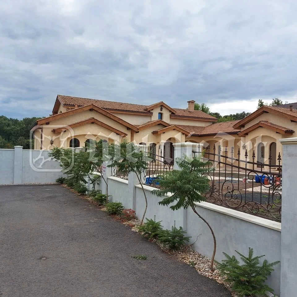 Gardul de-a lungul aleii, cu casa în spate.