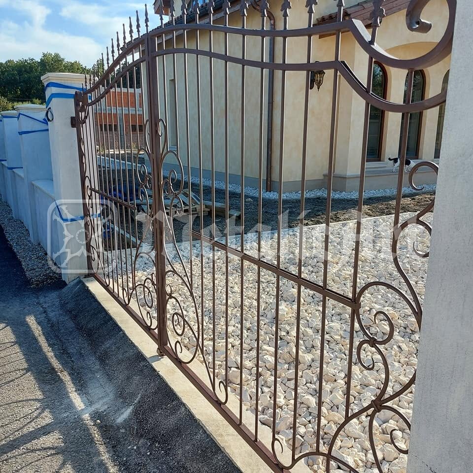 Poarta auto montată, încă în grund, cu casa în spate.