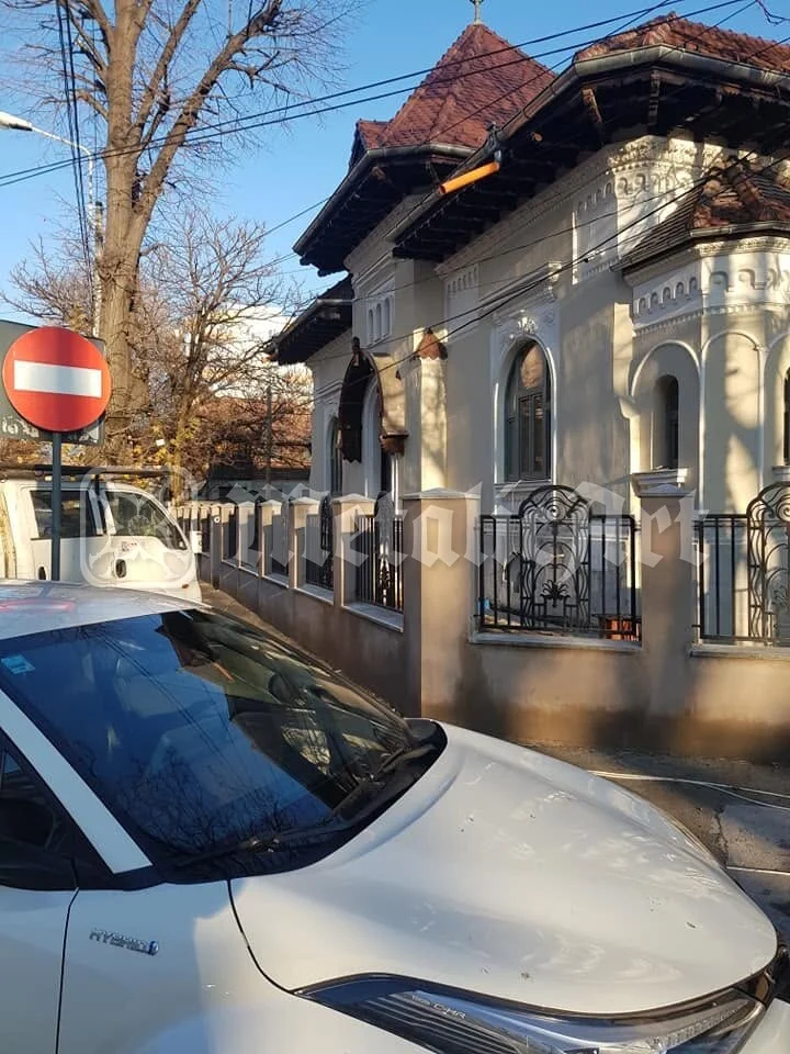 Casa și gardul, văzute de pe stradă, în lumina iernii.