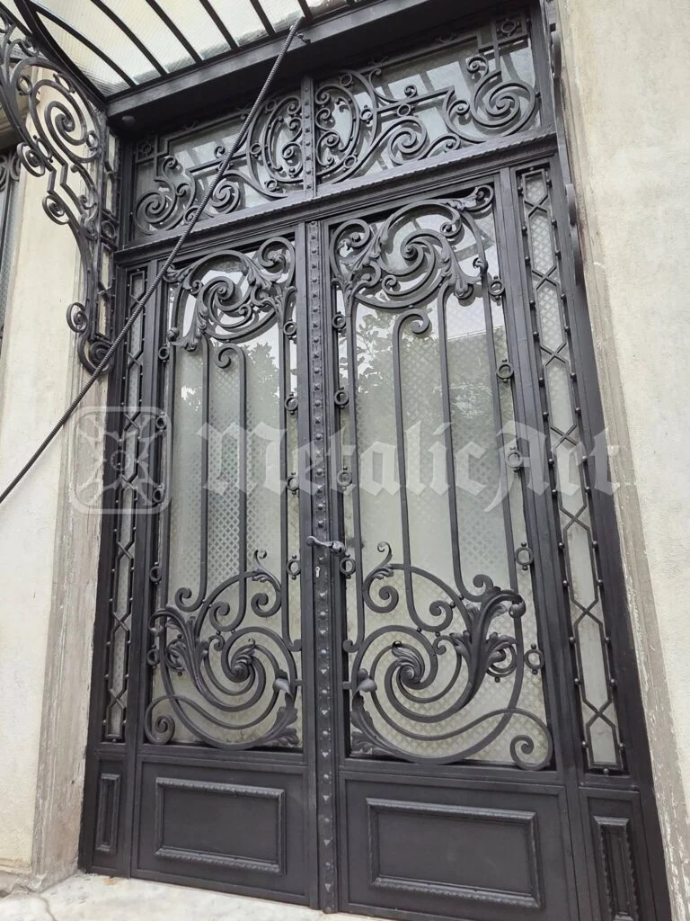 Ușa restaurată, văzută din față, cu volutele și geamurile mate.