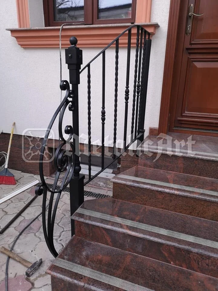 Treptele și balustrada, văzute din fața ușii de lemn.